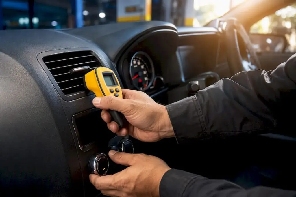 Technician checking car AC vent temperature