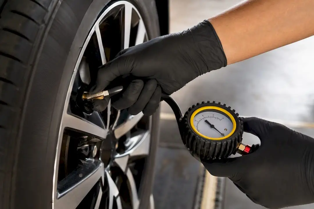 Technician measuring tire pressure with gauge