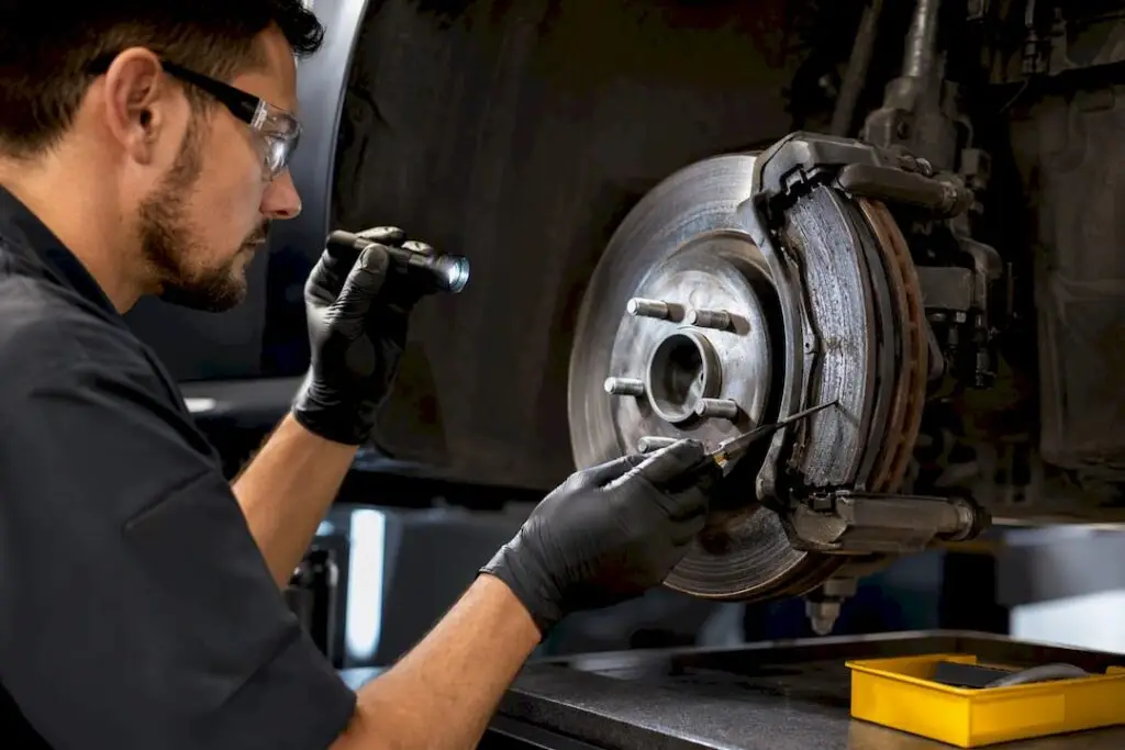 Technician inspecting worn brake rotor and pad