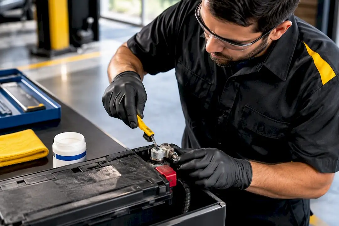 Technician cleaning corrosion from battery terminal